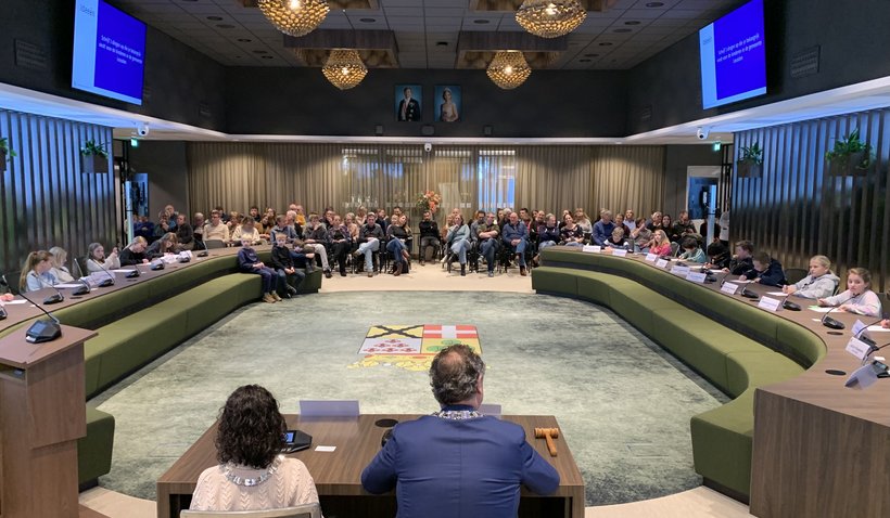 Burgemeester Gerolf Bouwmeester, kinderburgemeester Eva Matakupan en de Kindergemeenteraad met hun gasten in de raadzaal van Huis van Leusden.